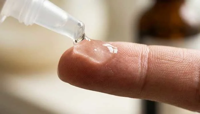 Close-up shot of clear snail mucin essence showing its thick, hydrating texture on a fingertip.